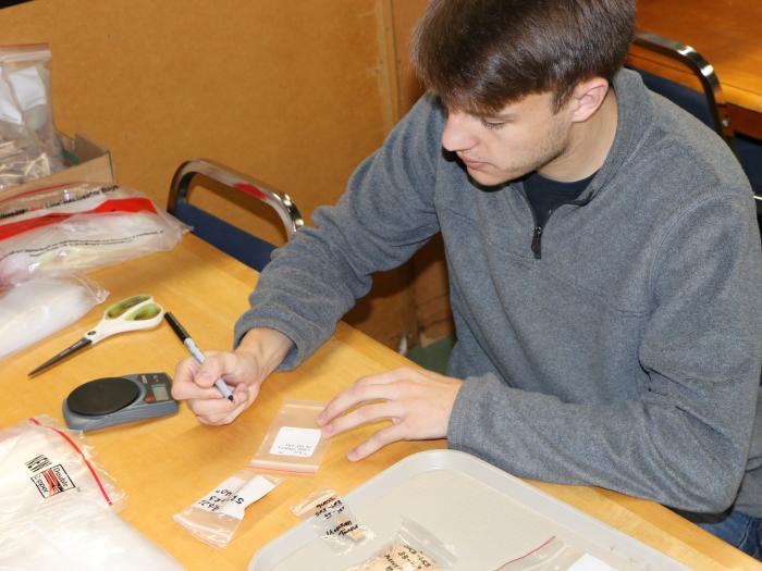 man writing on archival bags of artifacts