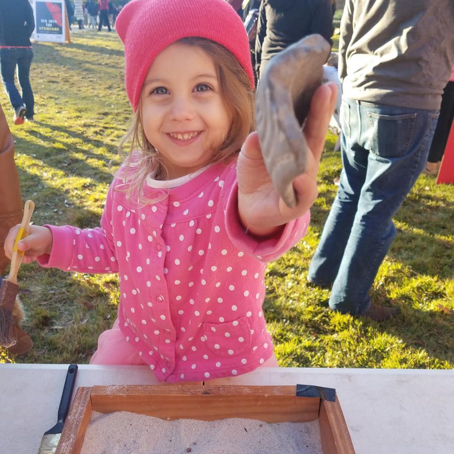 child holding a 3d printed artifact next to a mobile dig box