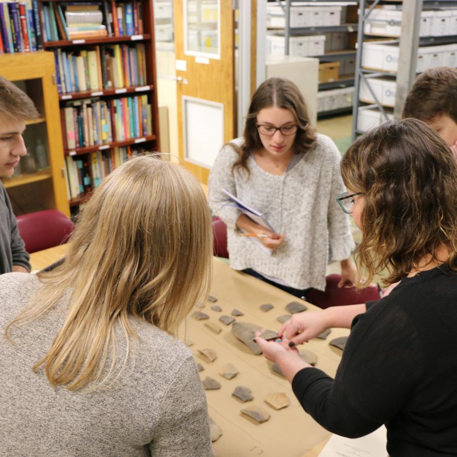 woman describing ceramics to two female and two male students
