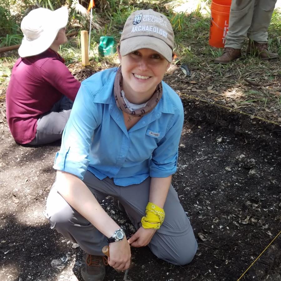 woman in an excavation unit holding a trowel